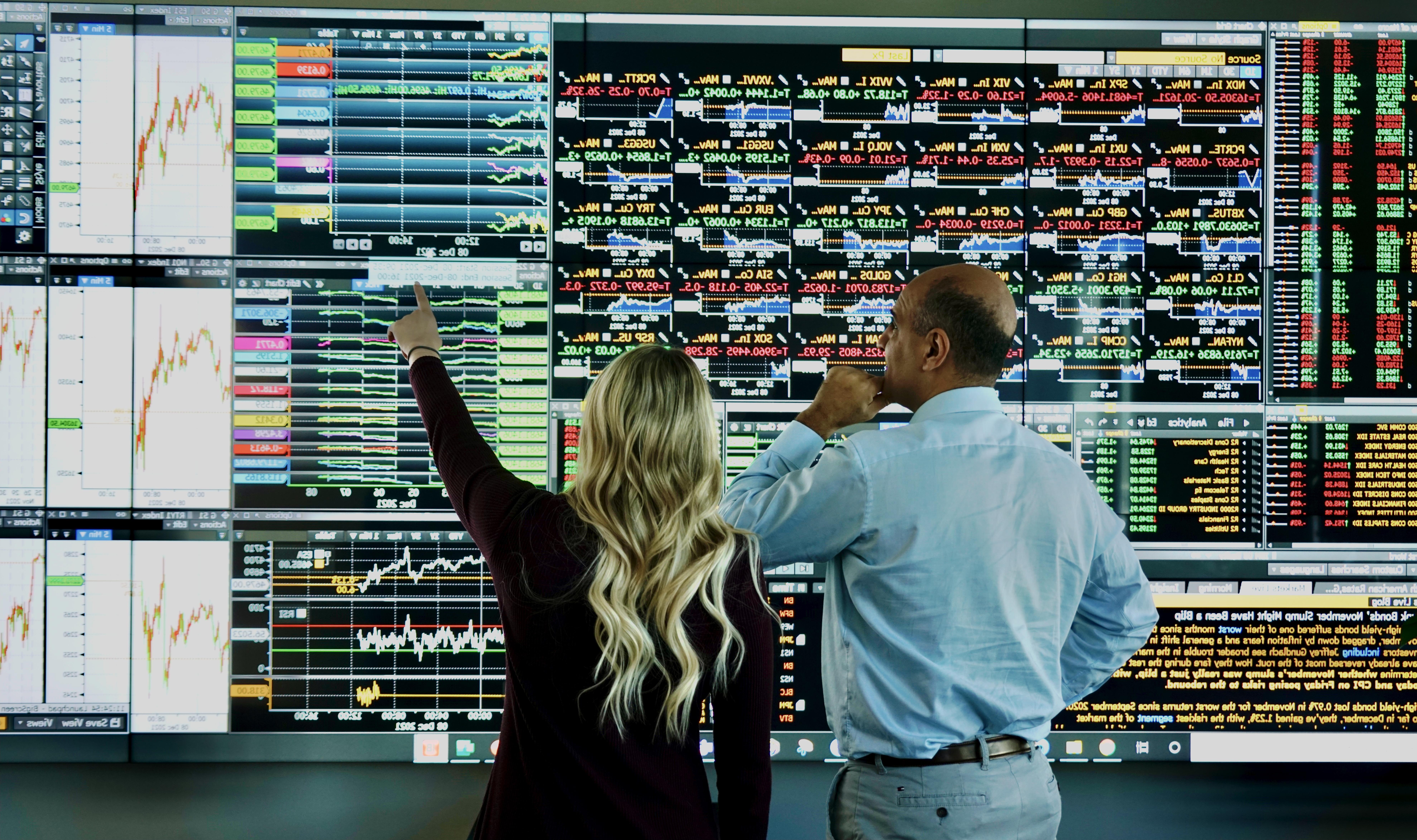 A student and professor reviewing stock analytics on a video board.